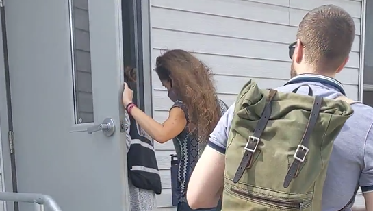 Refugee & Immigrant Program Director Sarah Brenes and Program Associate Tom Bird enter a trailer